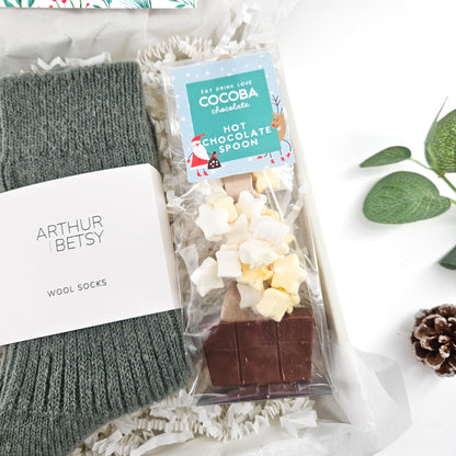 Close-up of Cocoba hot chocolate spoon with marshmallows and grey Arthur Betsy wool socks in The Cosy Christmas Night In Box.