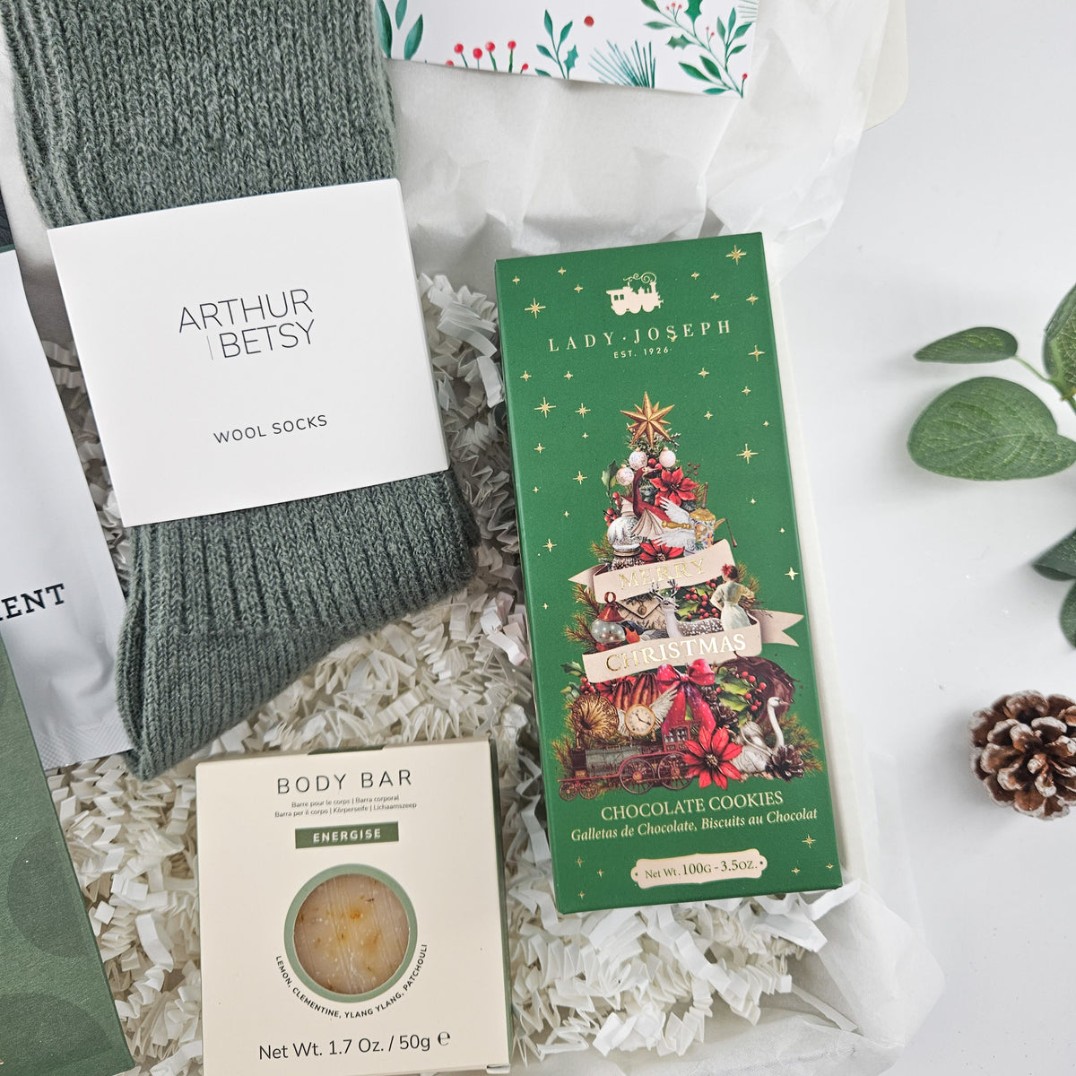 Close-up of cosy wool socks, Christmas chocolate biscuits and Energise body bar in a Christmas gift box for him.