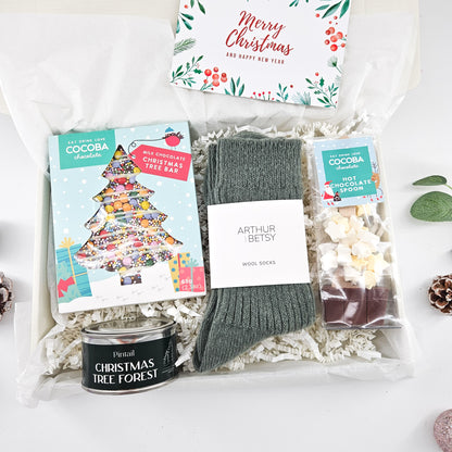 The Cosy Christmas Night In Box with chocolate Christmas tree, hot chocolate spoon, wool socks, festive scented candle and greeting card.